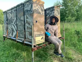 Pszczelarz przy pasiece mobilnej na przyczepie